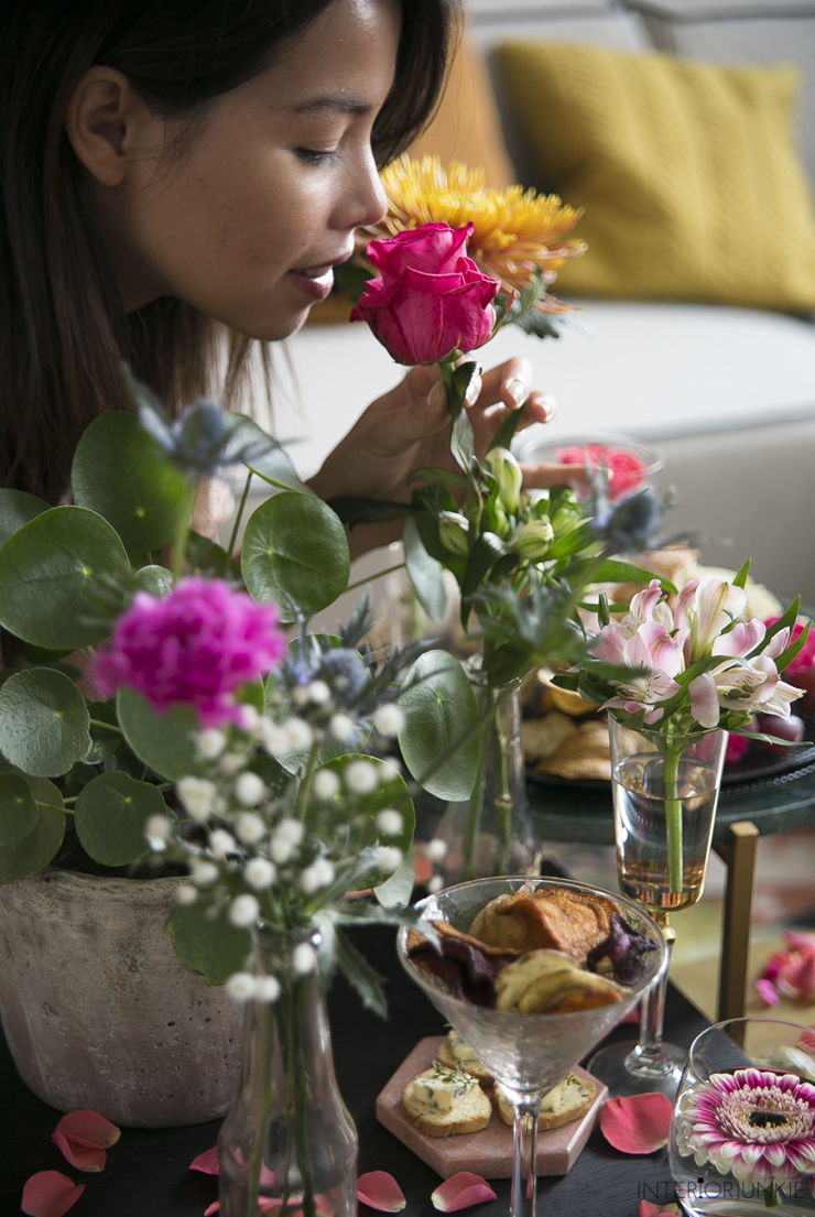 We kunnen dan wel richting winter gaan, maar in mijn hoofd is het nog volop zomer. Helemaal toen ik afgelopen weekend een shoot vol met bloemen had. Ik stylede mijn salontafeltjes geheel in de French Apéro stijl waar naast de hapjes uiteraard de zee aan bloemen alle aandacht trok. Nu ben ik niet vies van eten. Sterker nog: het liefst eet ik de hele dag door. Naast het toetje is ook zeker het aperitief favoriet bij mij. Tijdens mijn Toscaanse honeymoon at ik elke dag anti pasti, maar voor deze shoot staat de French Apéro centraal; een chic aperitiefje op z'n Frans, compleet met een baguette, Franse worst, kaasjes, groentechips en een mierzoete cocktail. Maar het zijn juist de bloemen waar ik even meer over wil vertellen, want deze fleurige figuranten uit deze smakelijke shoot zijn onmisbaar voor deze herfst. Ik som hieronder mijn favorieten op. Mijn salontafel gestyled met bloemen: French Apéro style! Een chrysant vol geluk De ultieme herfstbloem is natuurlijk de chrysant, uiteraard in zijn oorspronkelijke goudgele kleur. Ik weet niet beter dan dat mijn moeder tijdens de herfst altijd chrysanten kocht (en mij nog altijd elk jaar een bosje chrysanten geeft). Deze 'gouden' bloem , die trouwens ook in andere kleuren verkrijgbaar is, brengt warmte en kleur in je huis én staat voor geluk en gezondheid. En laten we nou net dat laatste nodig hebben tijdens de gure herfstmaanden. Voor altijd de jouwe met de Dahlia Een andere eyecatcher uit deze shoot is de Dahlia. Fotografeerde ik afgelopen jaar een enorme bos Dahlia's in mijn woonkamer, dit keer koos ik voor een iets subtieler exemplaar in een paarse kleur. Ik vind deze zo mooi: hij lijkt bijna nep. Deze Mexicaanse schone komt met de betekenis 'voor altijd de jouwe'. Past dus precies in mijn huis. Mijn salontafel gestyled met bloemen: French Apéro style! Bloem vol hartstocht, verlangen en romantiek Nog zo'n romantische bloem is de anjer, een bloem die nooit verveelt, omdat de anjer verschillende vormen en kleuren heeft. Voor deze shoot nam ik een felroze, een van mijn lievelingskleuren voor bloemen. Hij zit gezellig in een flesje met gipskruid en de distel. Deze laatste heeft niet zo'n mooie betekenis (afweer, zorg en kommer), maar steekt qua kleur mooi af bij de rest. En wist je dat gipskruid in de verte familie is van de anjer? Mijn salontafel gestyled met bloemen: French Apéro style! Gerbera Verrassend maar waar, maar de gerbera heeft én geen geur én geen symboliek. Toch vond ik dat deze bloem niet mocht ontbreken op mijn salontafel. Ik knipte de gerbera extra korte en stylede 'm in twee glaasjes. salontafel-bloemen-interiorjunkie25 * Dit is een inspirerende samenwerking met Bloemenbureau Holland. Door samen te werken met merken, kan Interior Junkie blijven bestaan. Thanks voor de support!