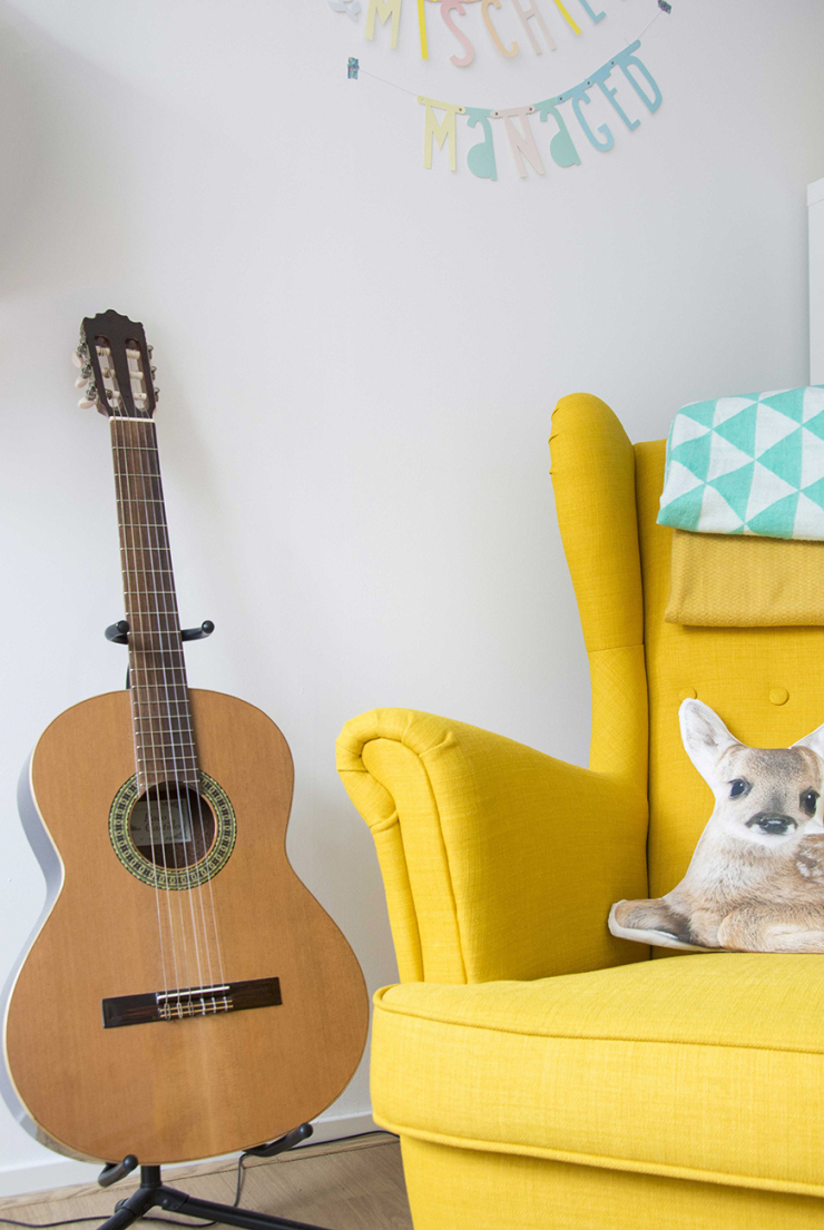 Mijn gele stoel en gitaar. De stoel komt van IKEA en het kleed van HEMA. Het Bambi kussen kocht ik bij Xenos.